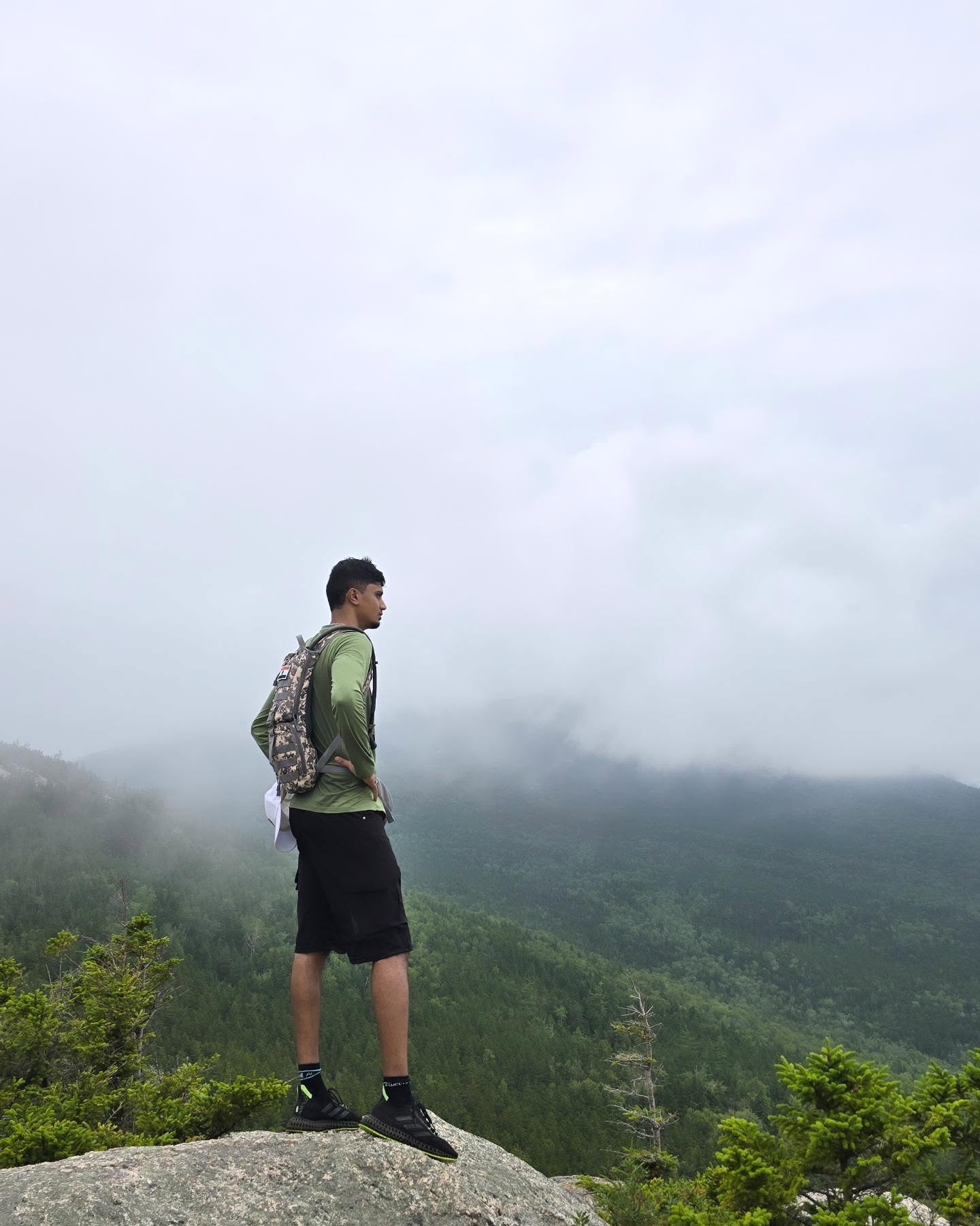 Dinesh on a misty mountain summit above the cloud line
